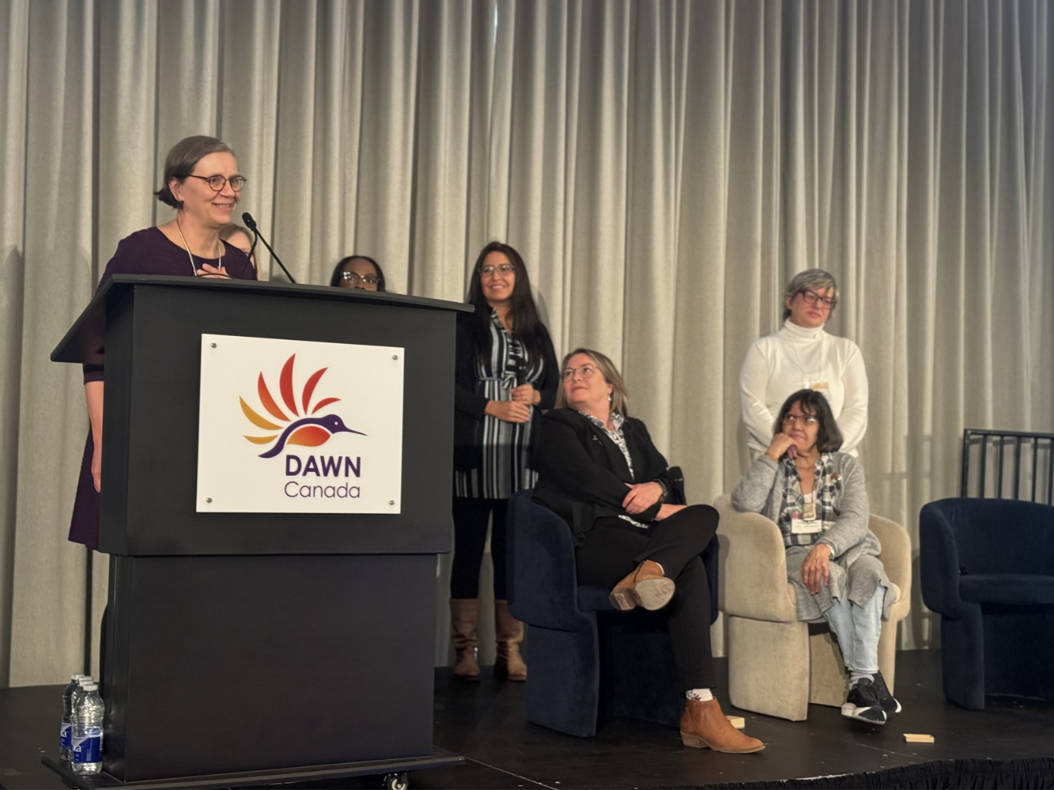 Photo of the 2023 Hummingbird Awards Recipients, Sandra Pronteau and Deborah Stienstra from the Live Work Well Research Centre, standing on stage with Maureen Haan from the CCRW and Evelyn Huntjens and Bonnie Brayton from DAWN Canada