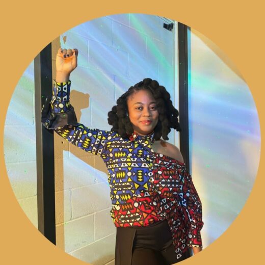 A woman standing with fist in the air, wearing colourful African print