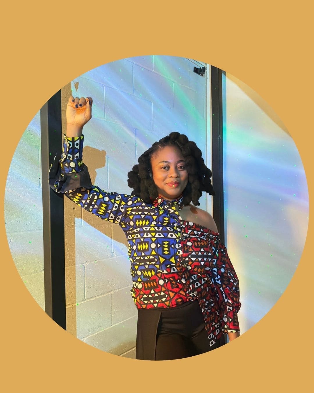 A woman standing with fist in the air, wearing colourful African print