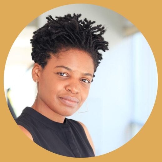 A Black woman wearing a black shirt, head tilted toward camera, smiling