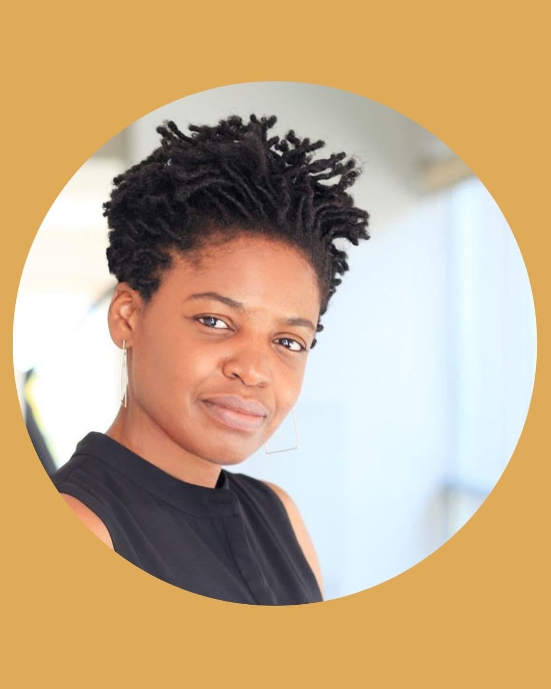 A Black woman wearing a black shirt, head tilted toward camera, smiling