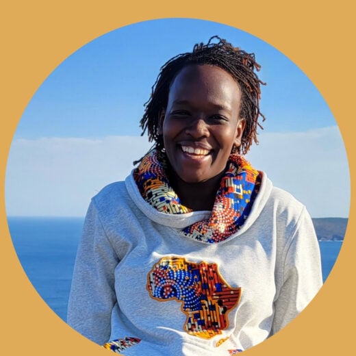 Yellow frame with Salome in the middle. Salome has black and brown twist hair, black skin tone and smiling. She is wearing a grey sweater with bright African design in the hood and the shape of Africa on the front.